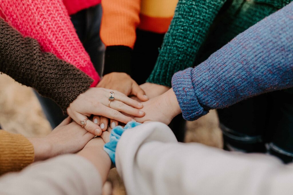 Group of people stood in a circle stacking hands in the centre of the circle